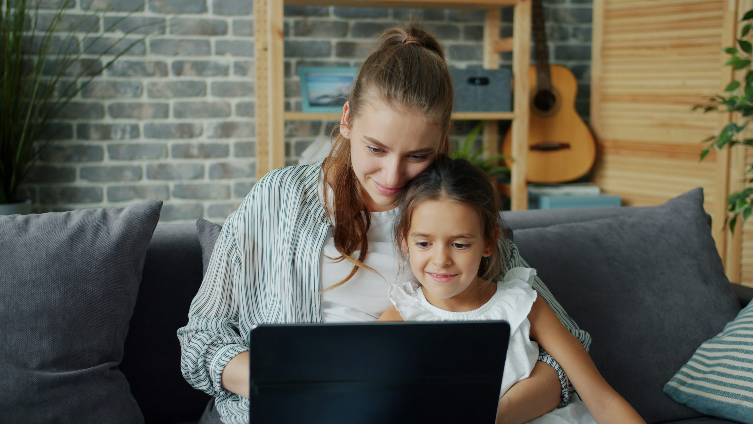 Adulto e criança usando computador portátil em mesa de casa.