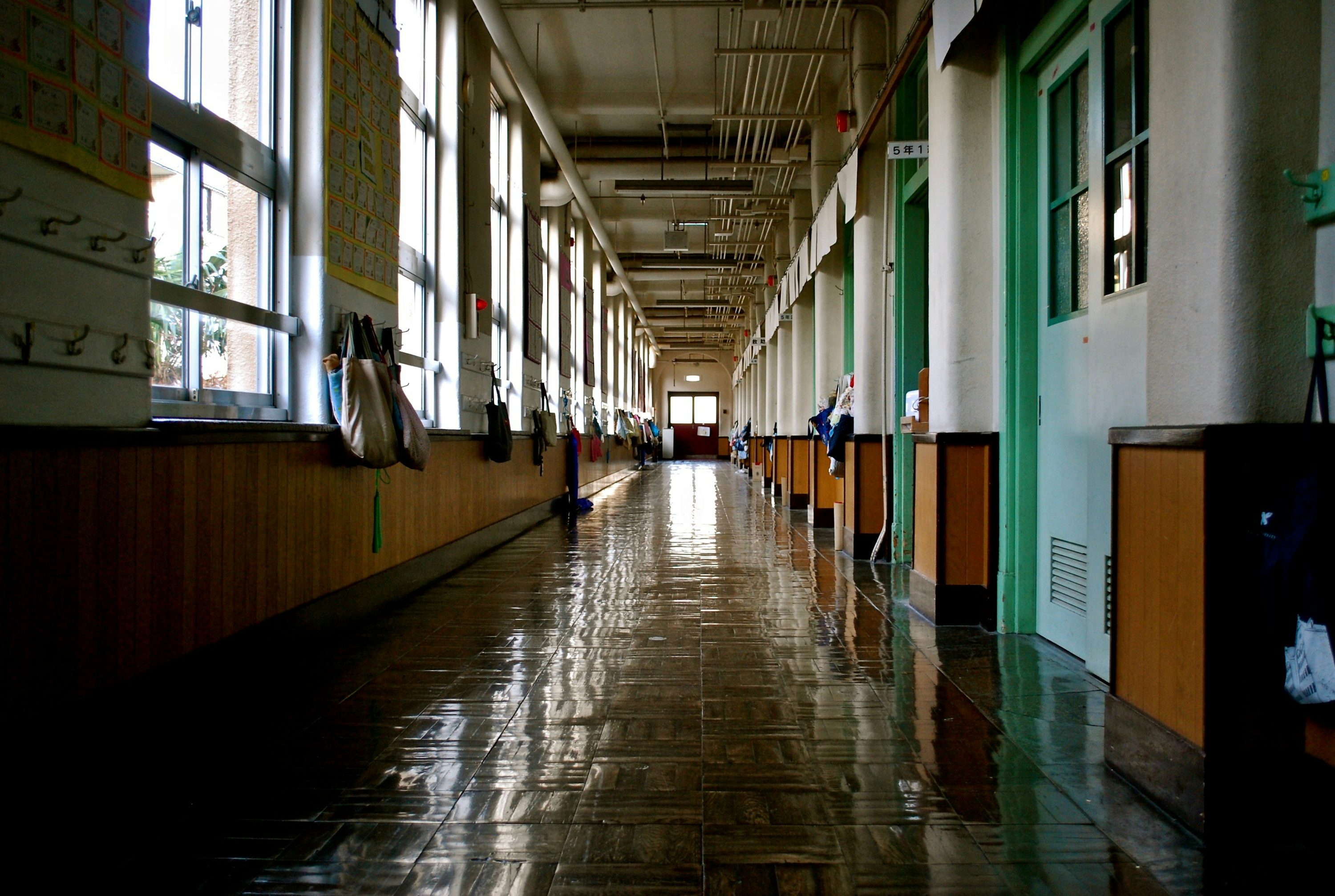 Corredor escolar vazio com janelas e luz natural.