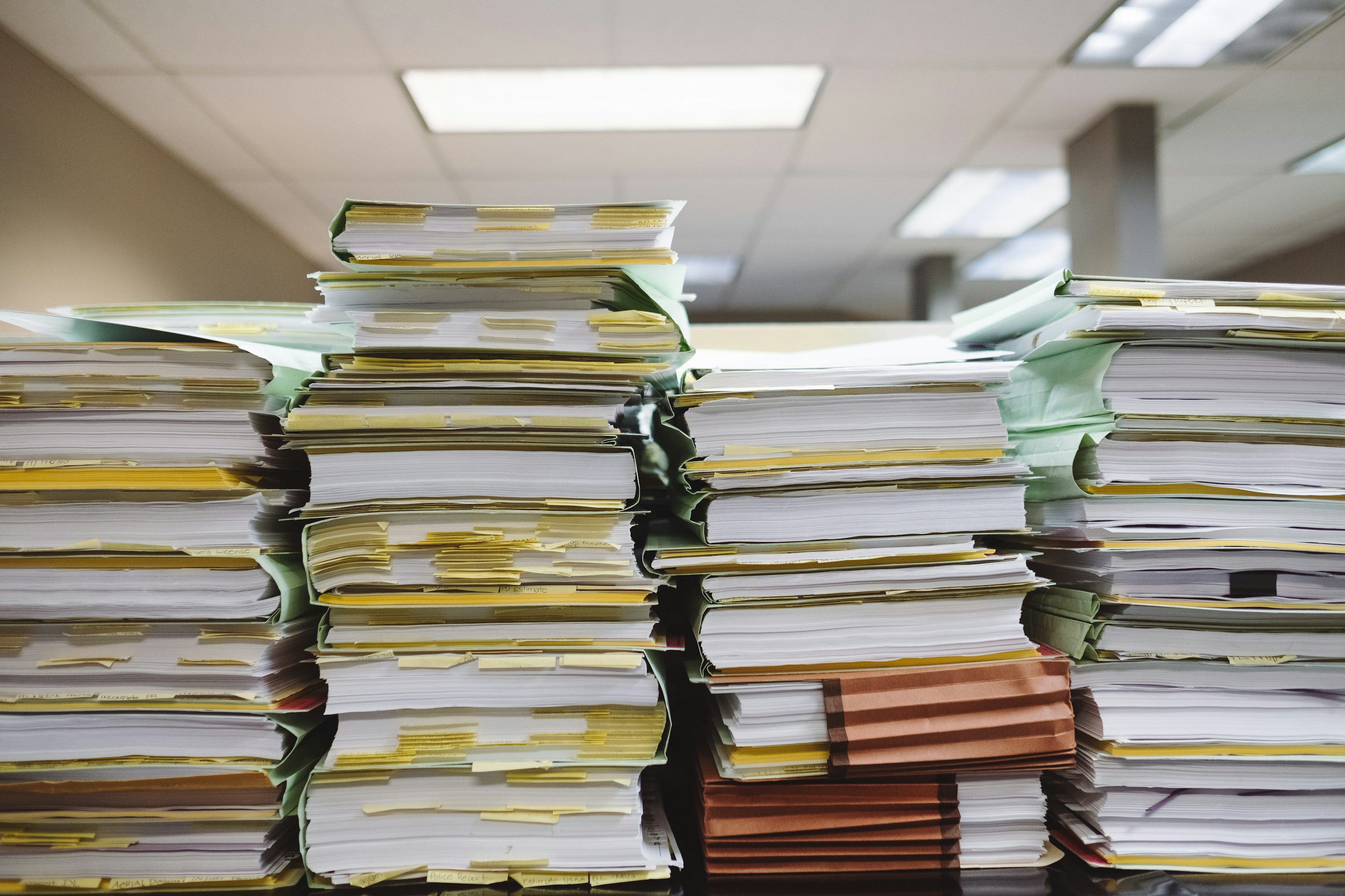 Pilha de documentos e pastas organizadas sobre uma mesa de escritório.