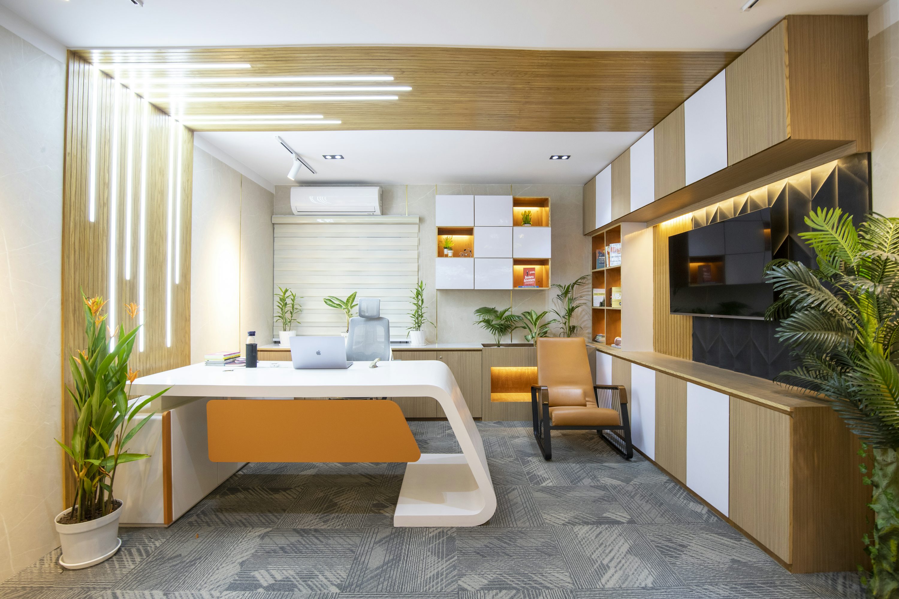 Interior de escritório com mesa coletiva, plantas e luminárias modernas.