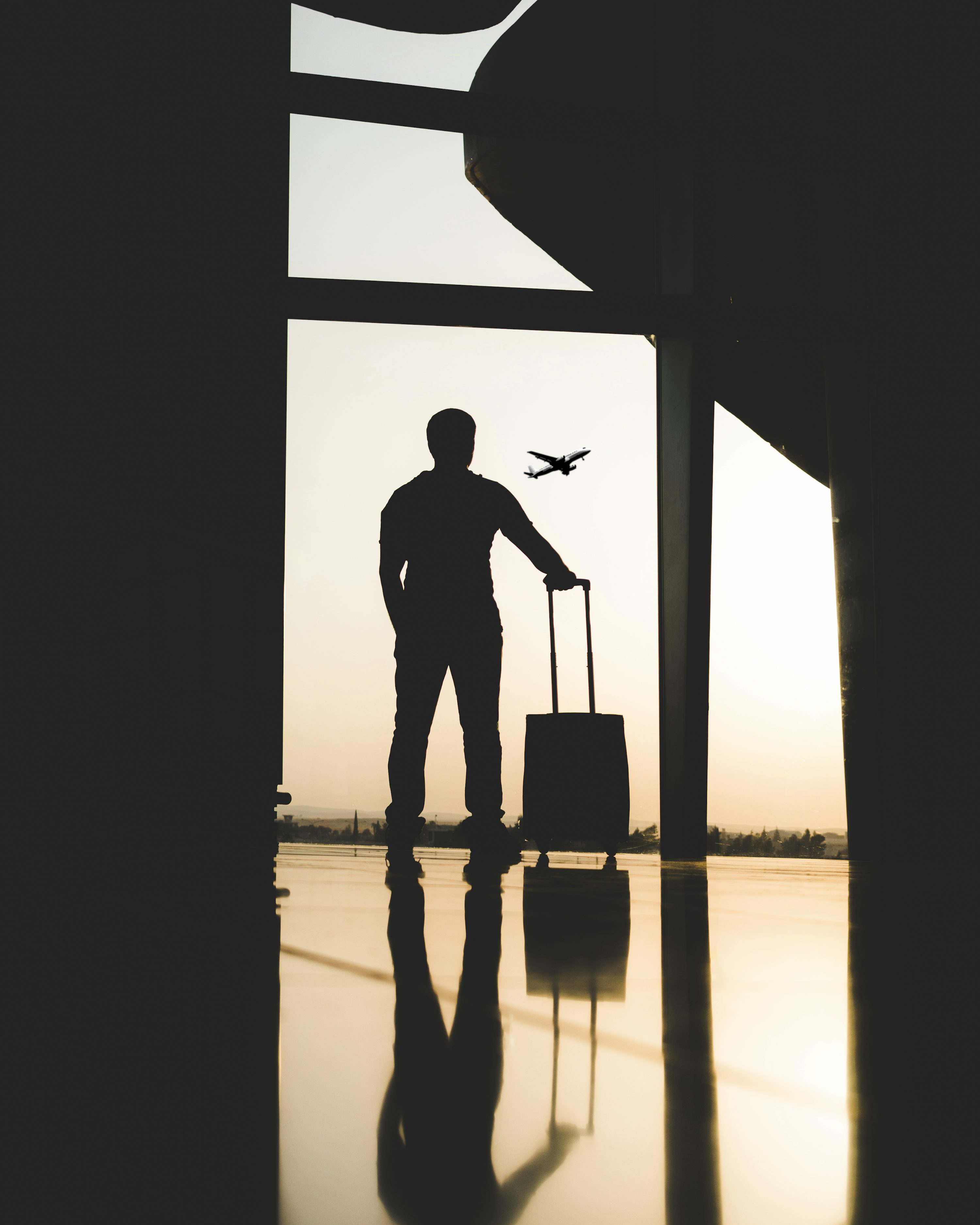 Viajante com mala em área de embarque de aeroporto ao amanhecer.