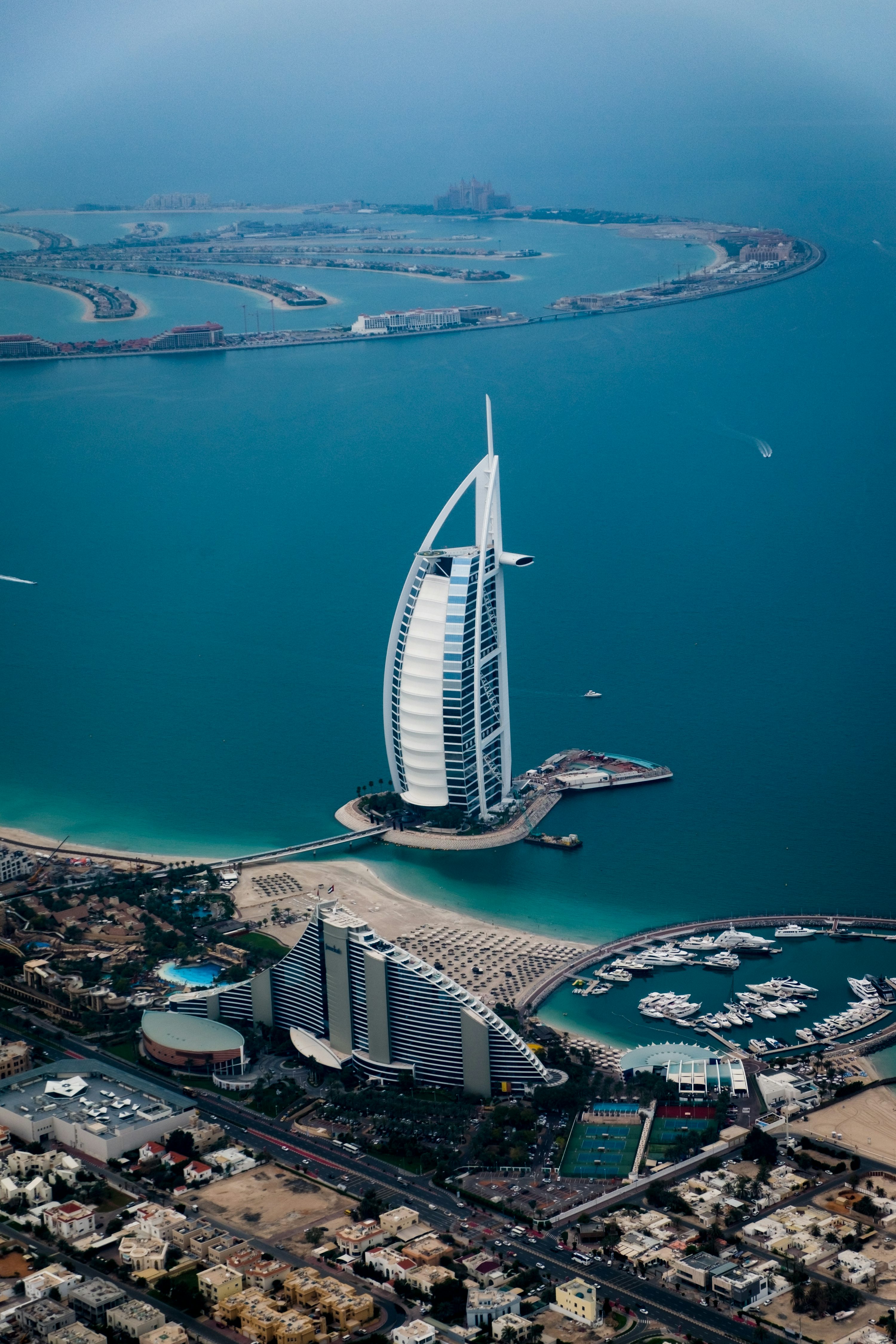Vista aérea do litoral de Dubai com o Burj Al Arab e áreas urbanas.