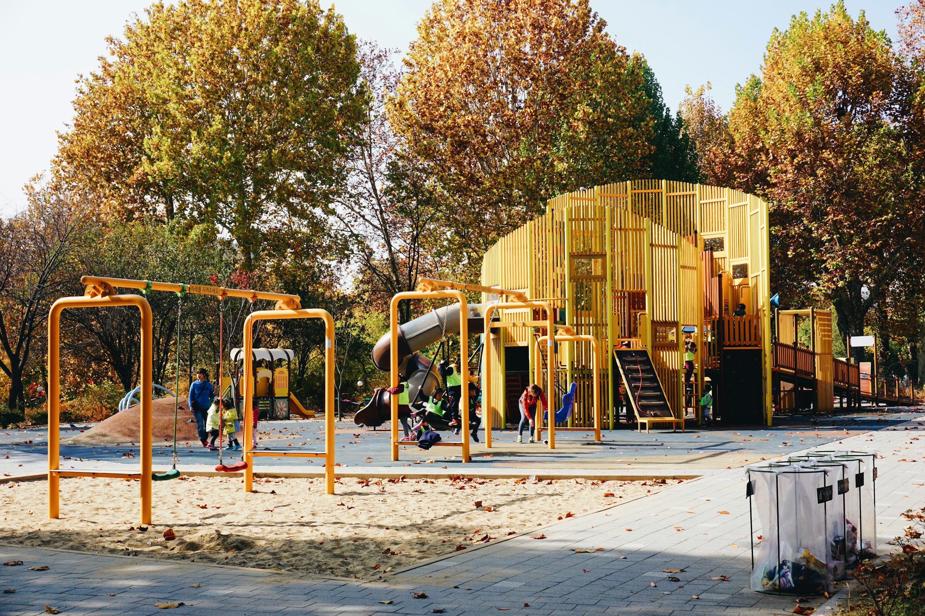 Playground com balanços e árvores em área externa.