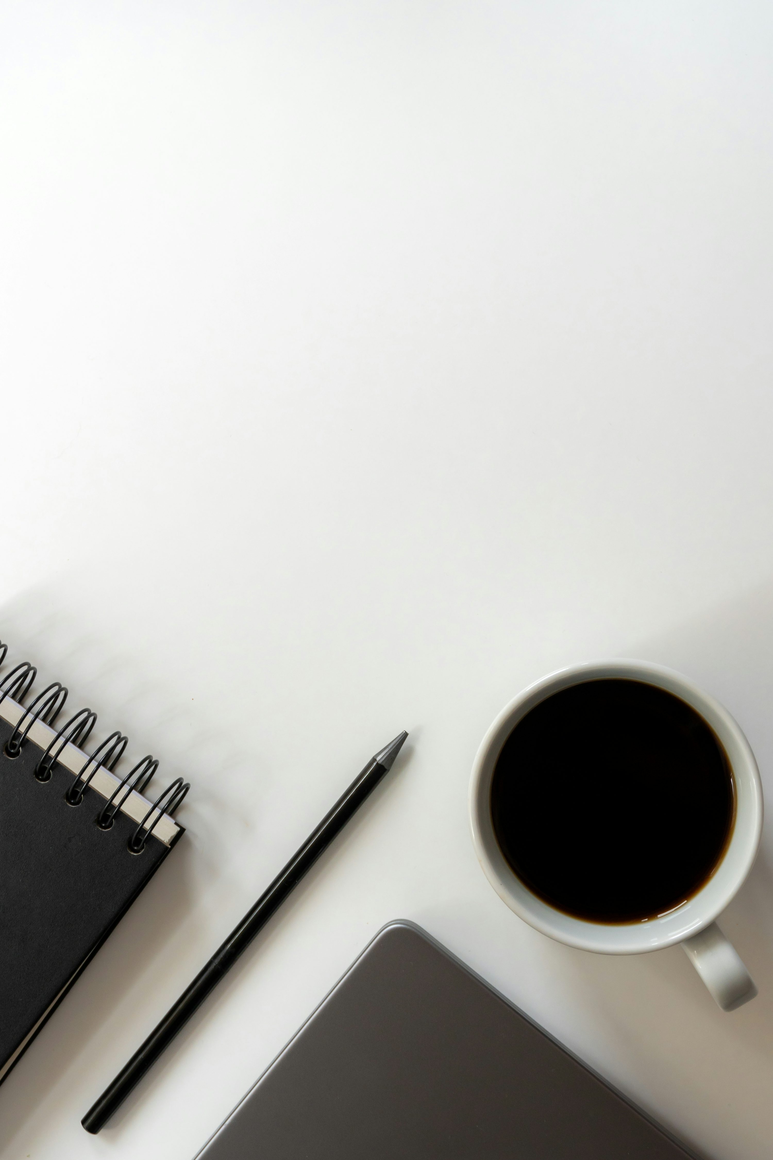 Caderno, caneta, café e computador em mesa de trabalho.