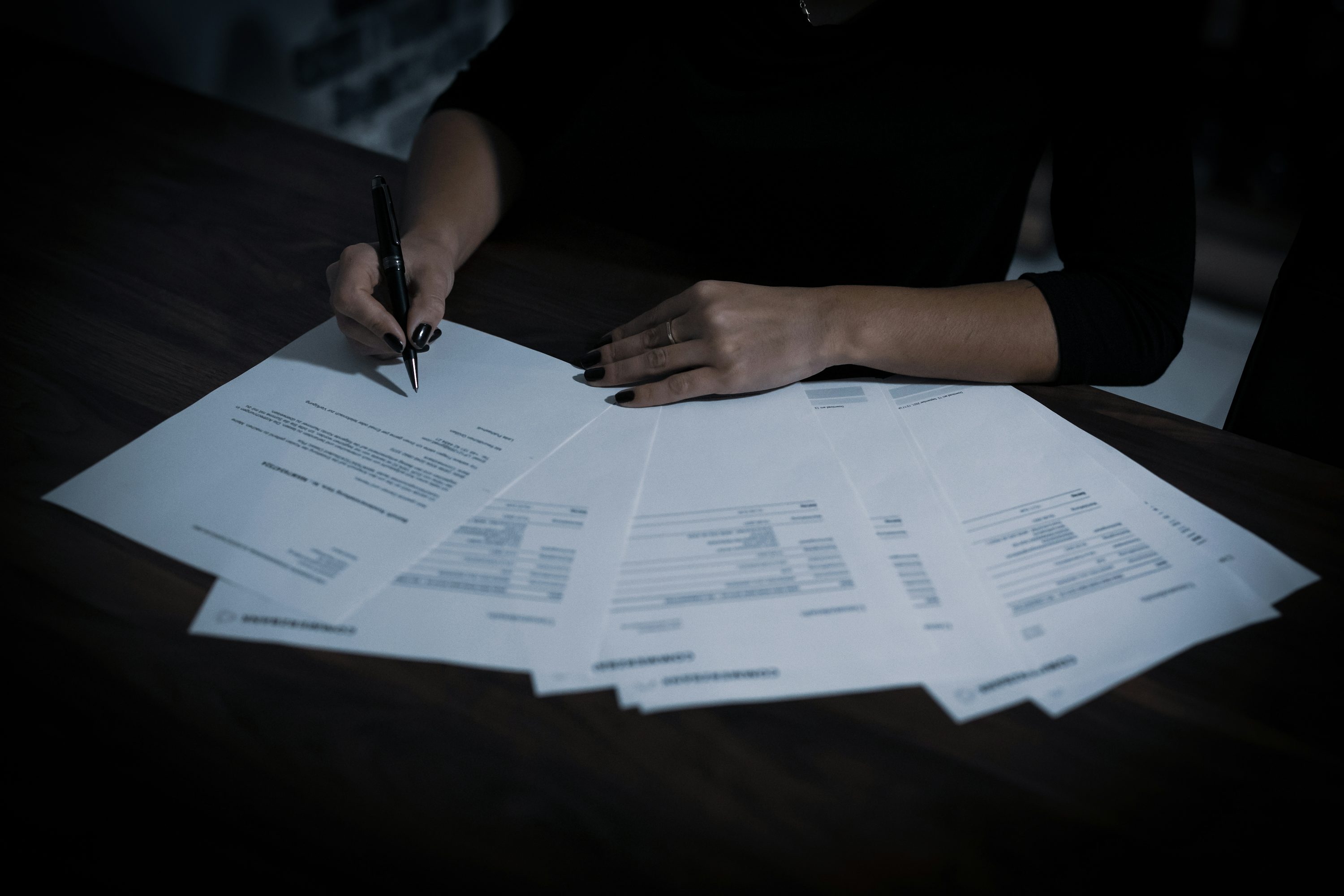 Pessoa preenchendo documentos em uma mesa.