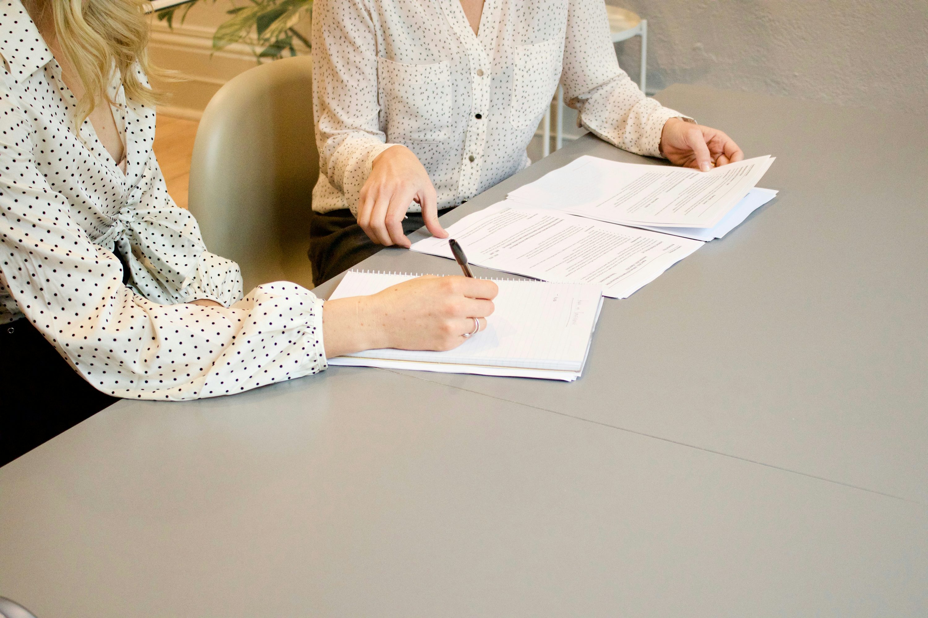 Duas pessoas analisando documentos sobre uma mesa.