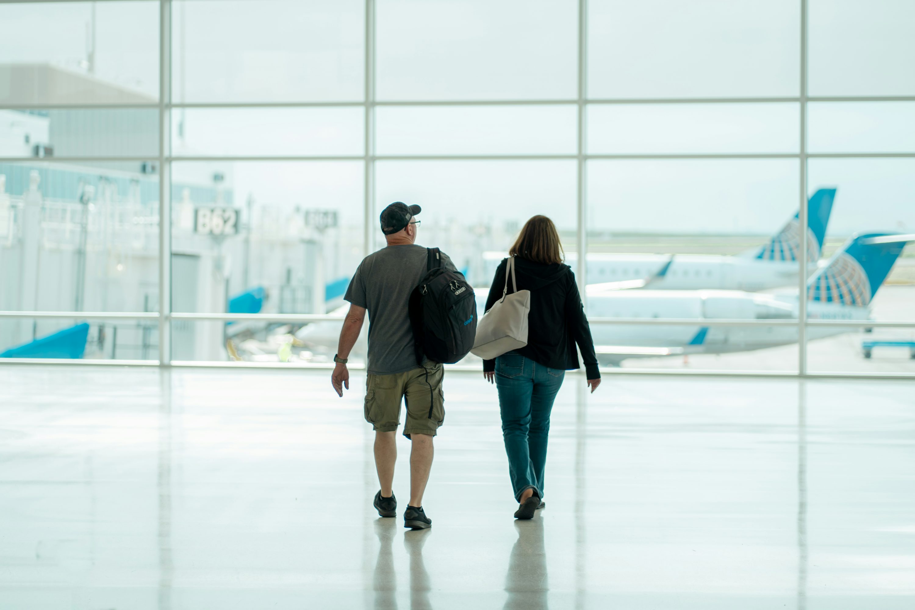 Viajantes caminhando em saguão de aeroporto iluminado.