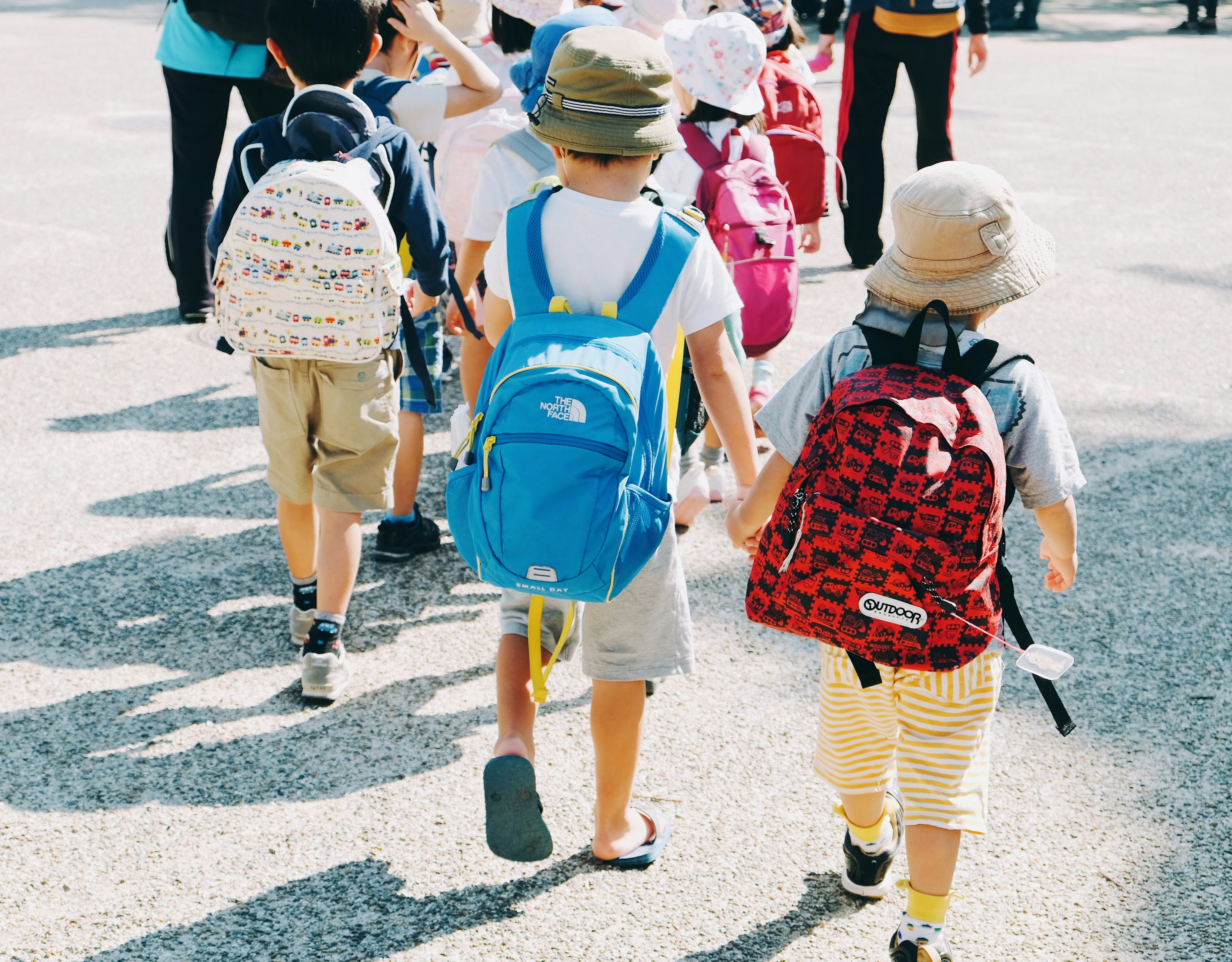 Mochilas coloridas de crianças em área externa de escola.