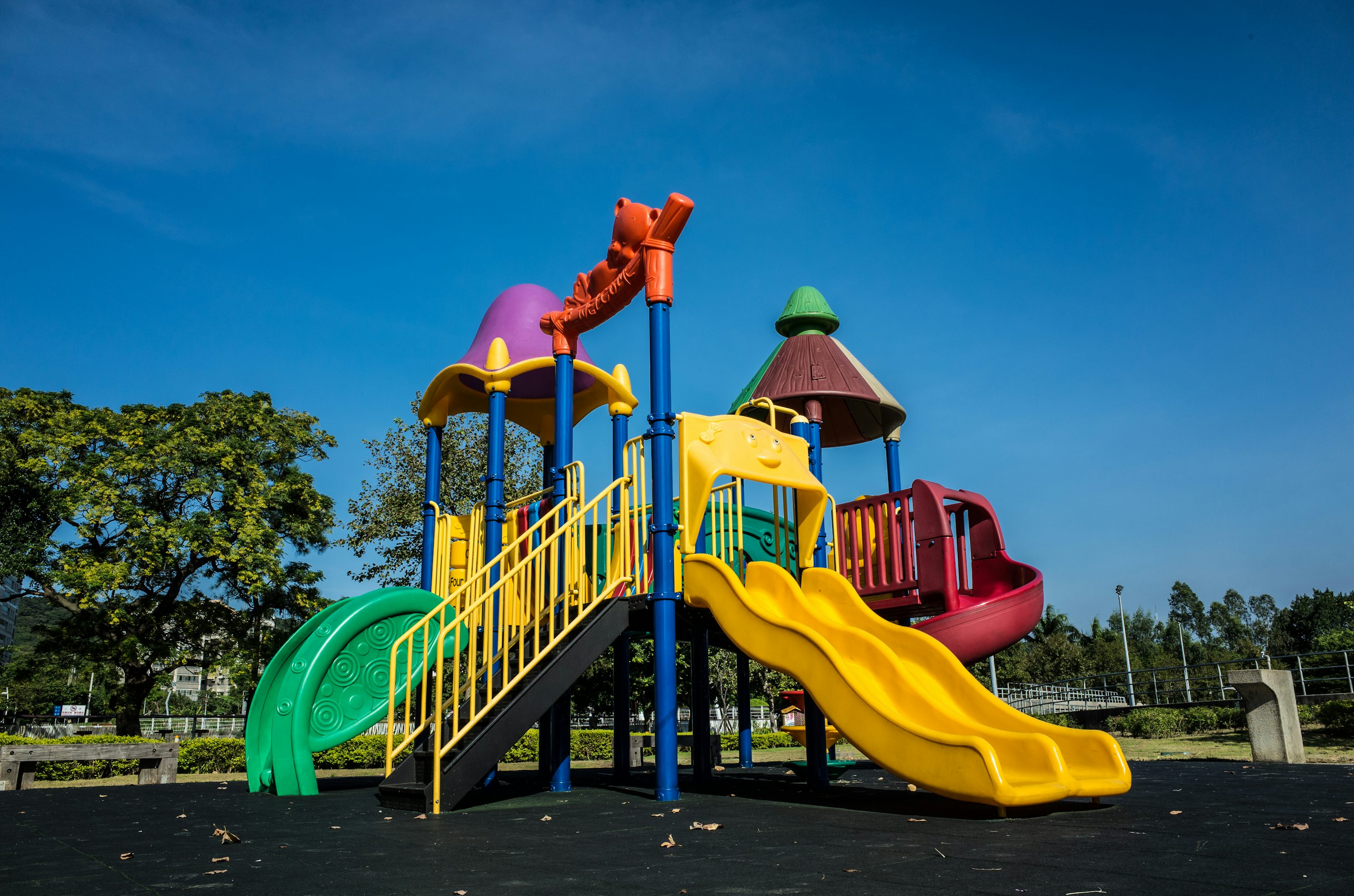 Parque infantil vazio com escorregador colorido sob céu azul.