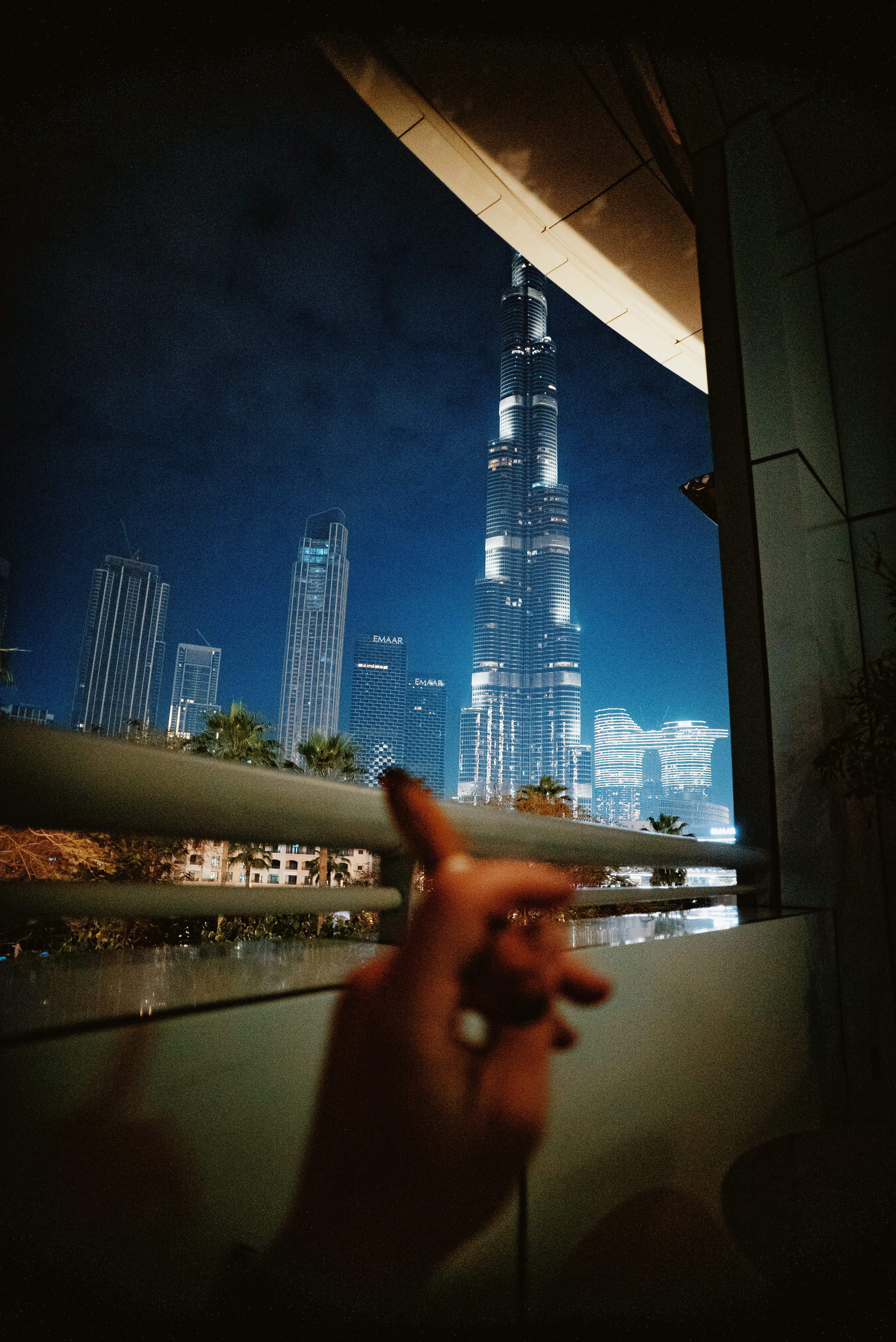 Pessoa usando telefone celular diante do horizonte iluminado de Dubai.