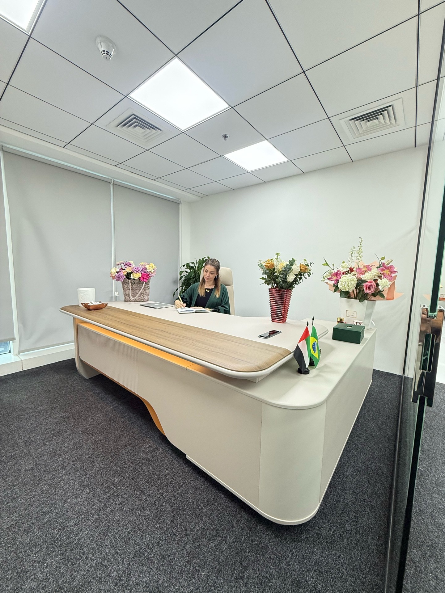 Mariane Nunes, empresária brasileira em Dubai, sentada à mesa de trabalho em escritório