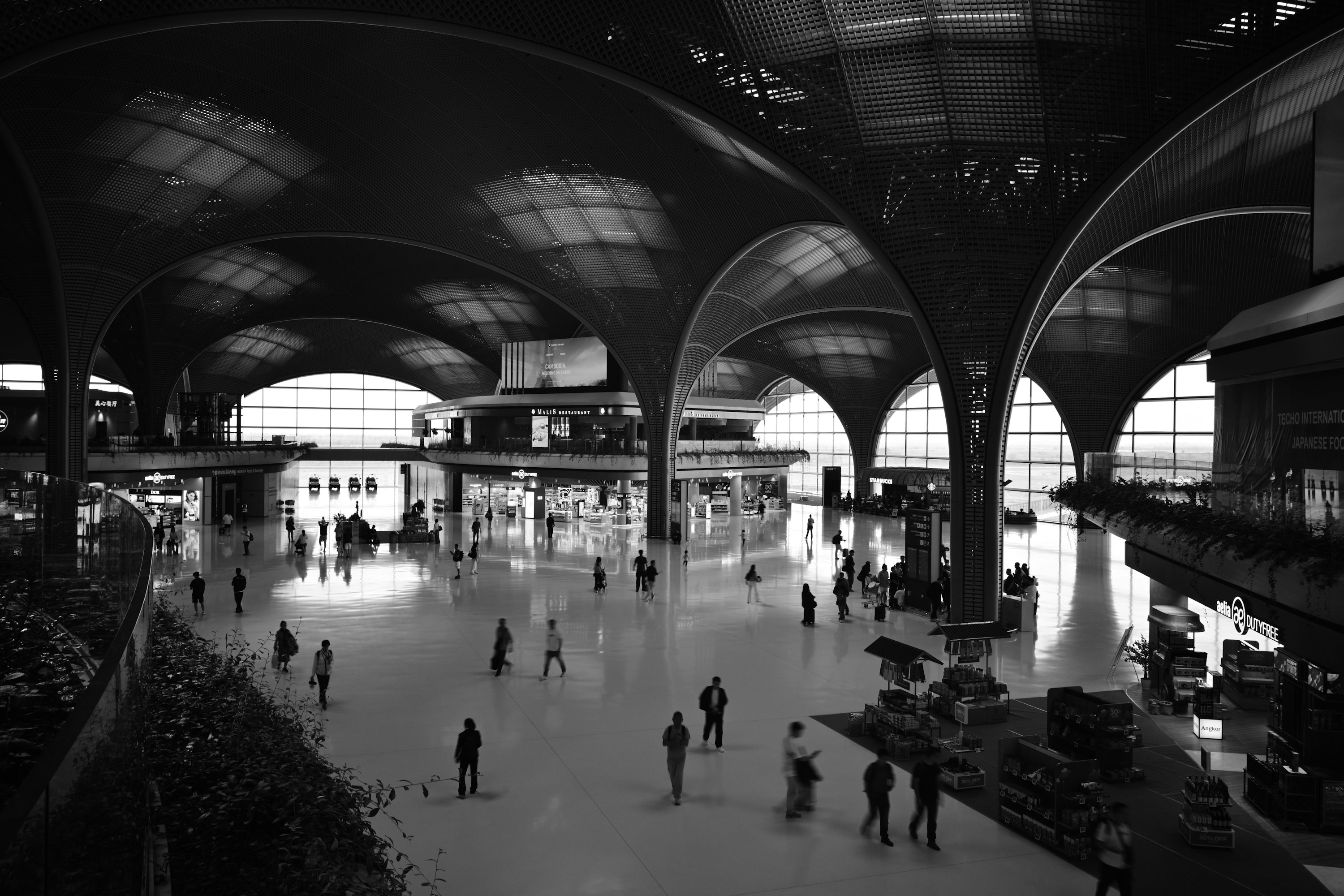 Pessoas caminhando em um amplo terminal de aeroporto.