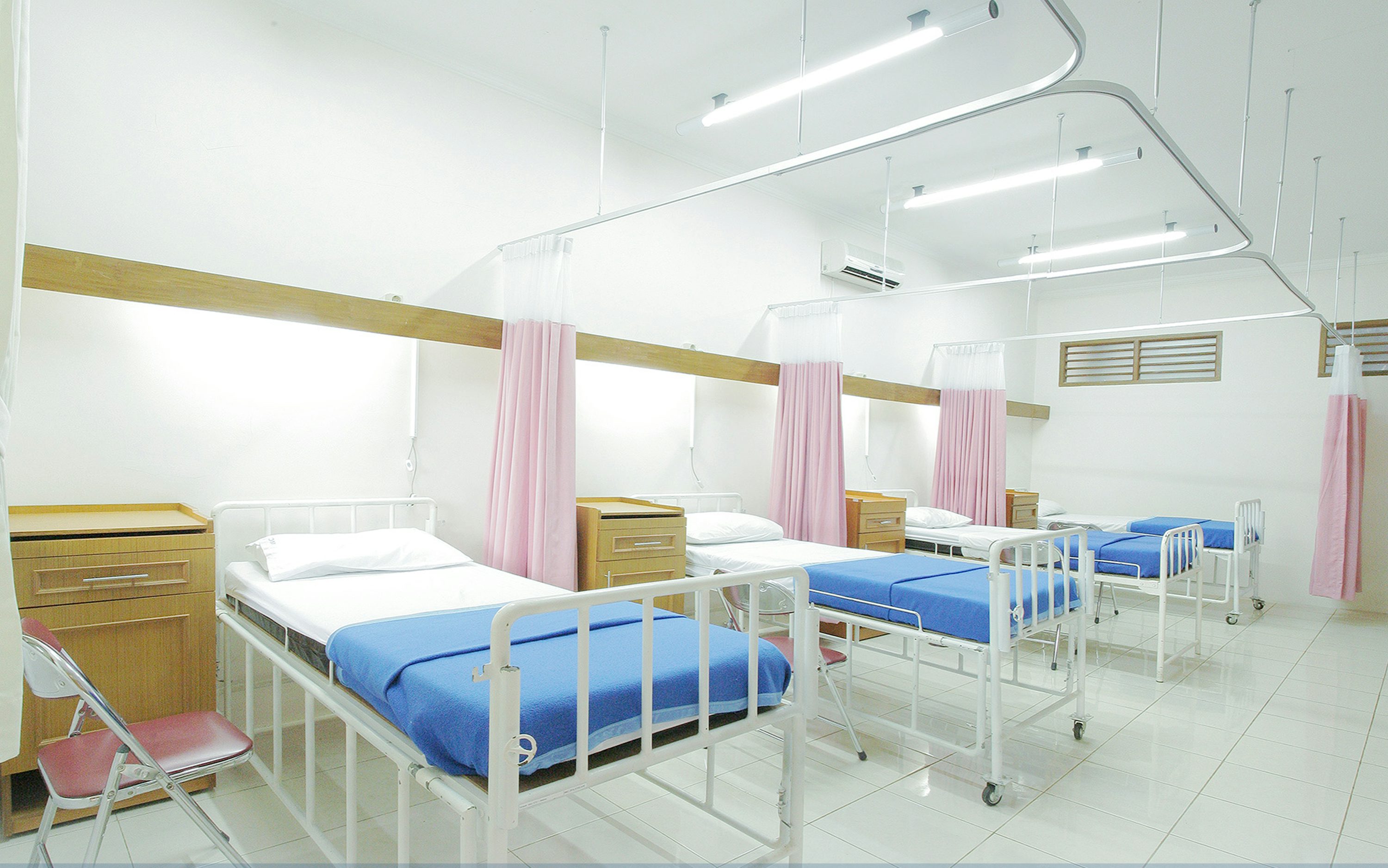 Quarto hospitalar com leitos e equipamentos médicos em ambiente interno.