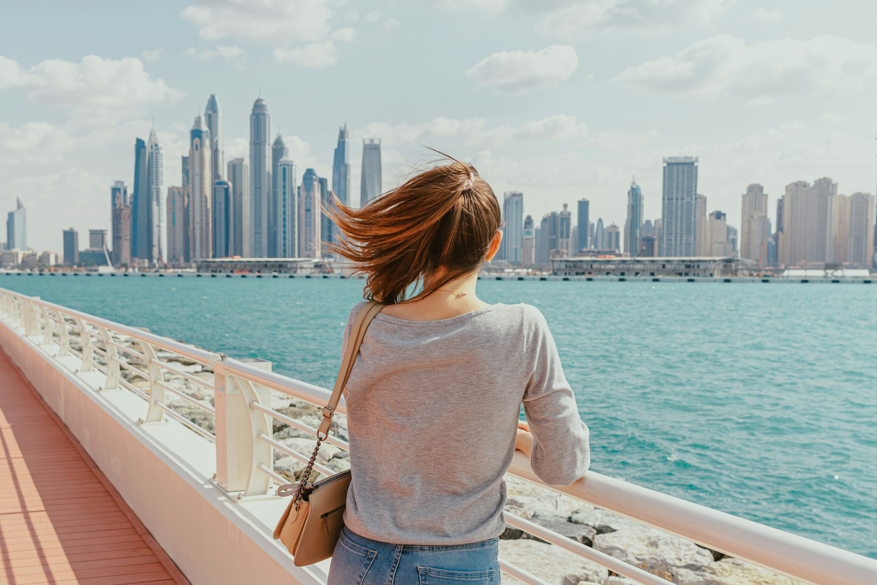 Mulher observando o horizonte de Dubai a partir de uma embarcação ao entardecer.