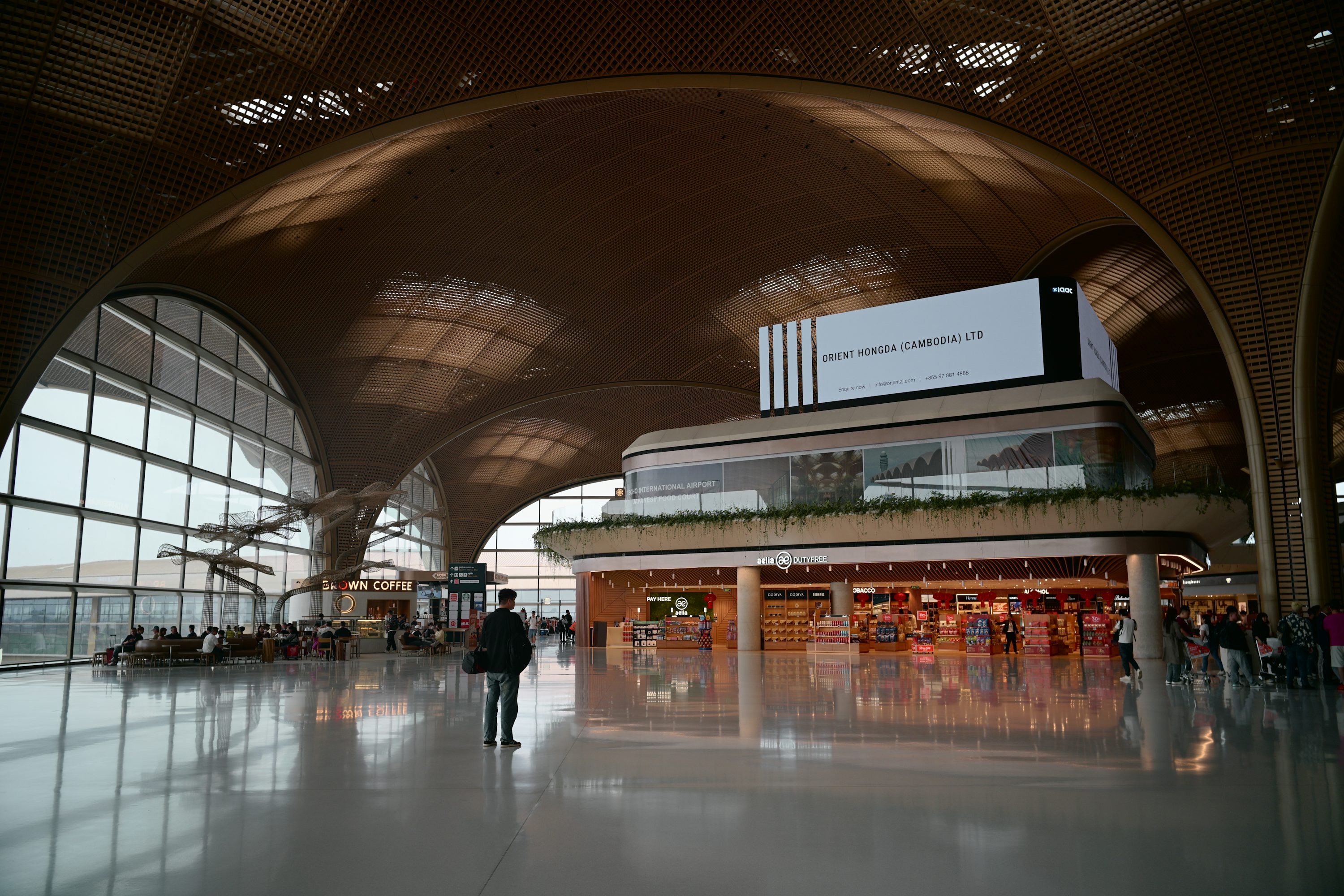 Interior de terminal de aeroporto com janelas altas e assentos.