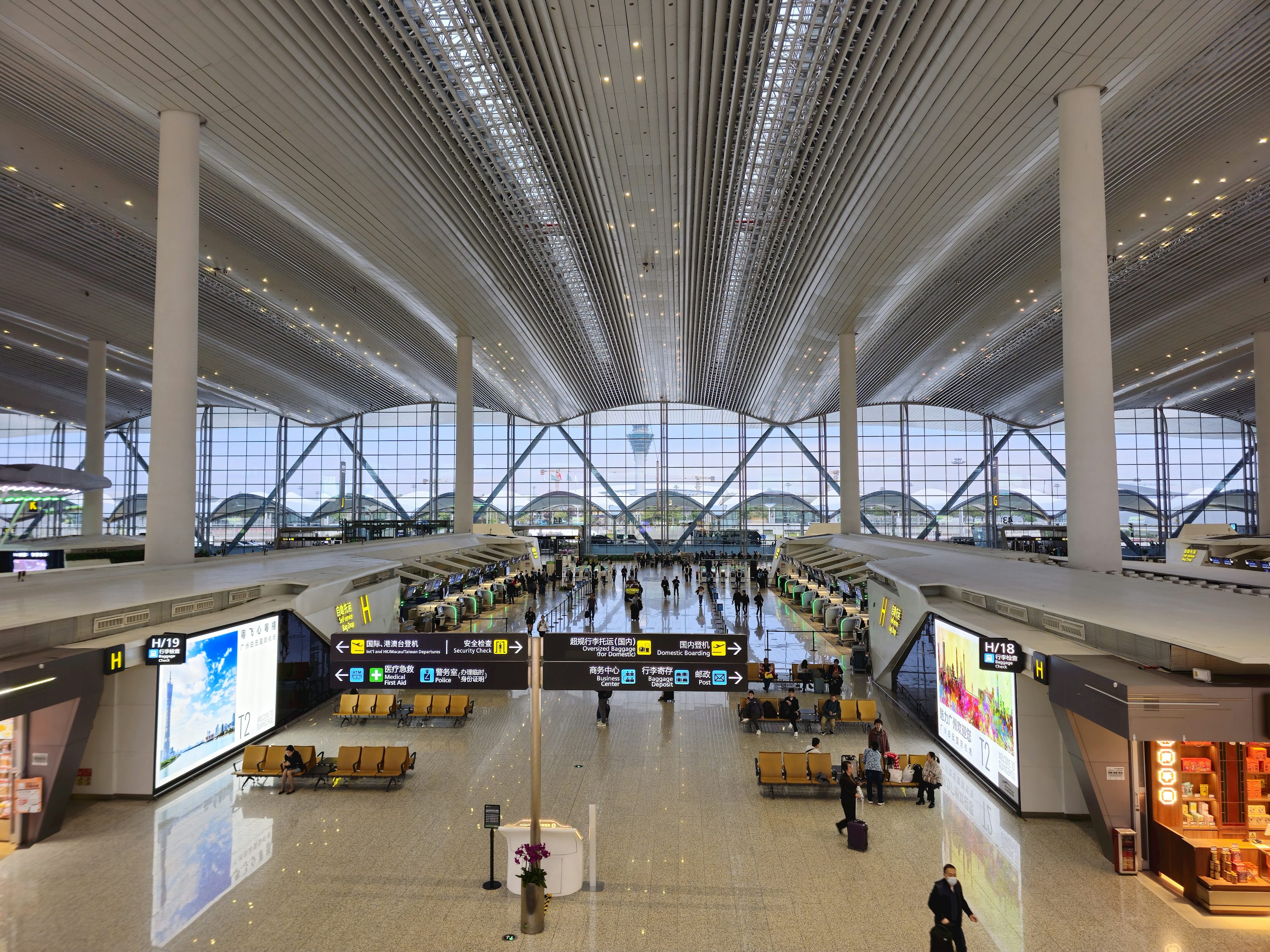 Vista interna de aeroporto com teto iluminado e áreas de circulação.
