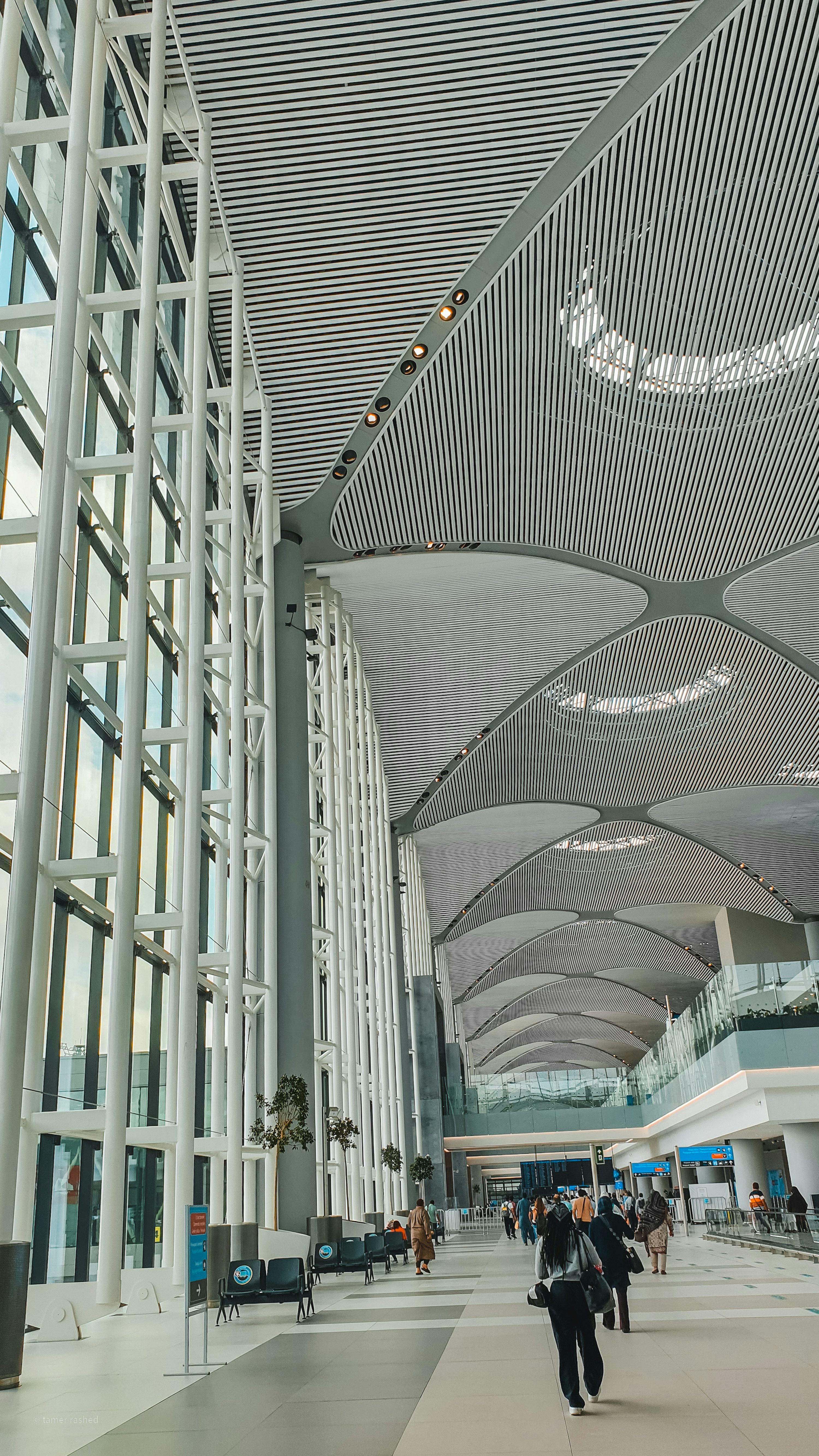 Terminal de aeroporto com arquitetura curva e pessoas ao fundo.